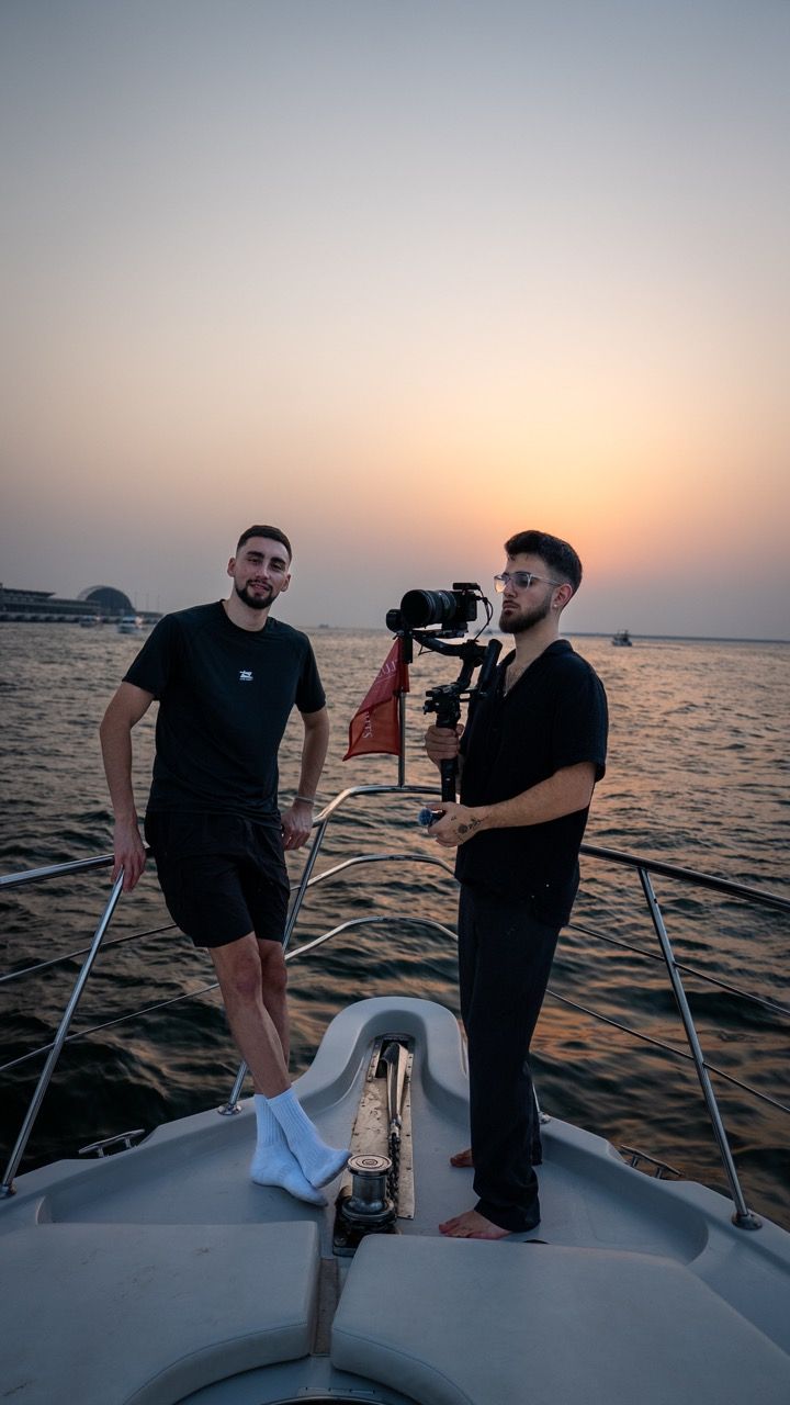 Die Gründer von Ziya Media, Andy und Orkan, mit Kamera auf einer Yacht bei Sonnenuntergang